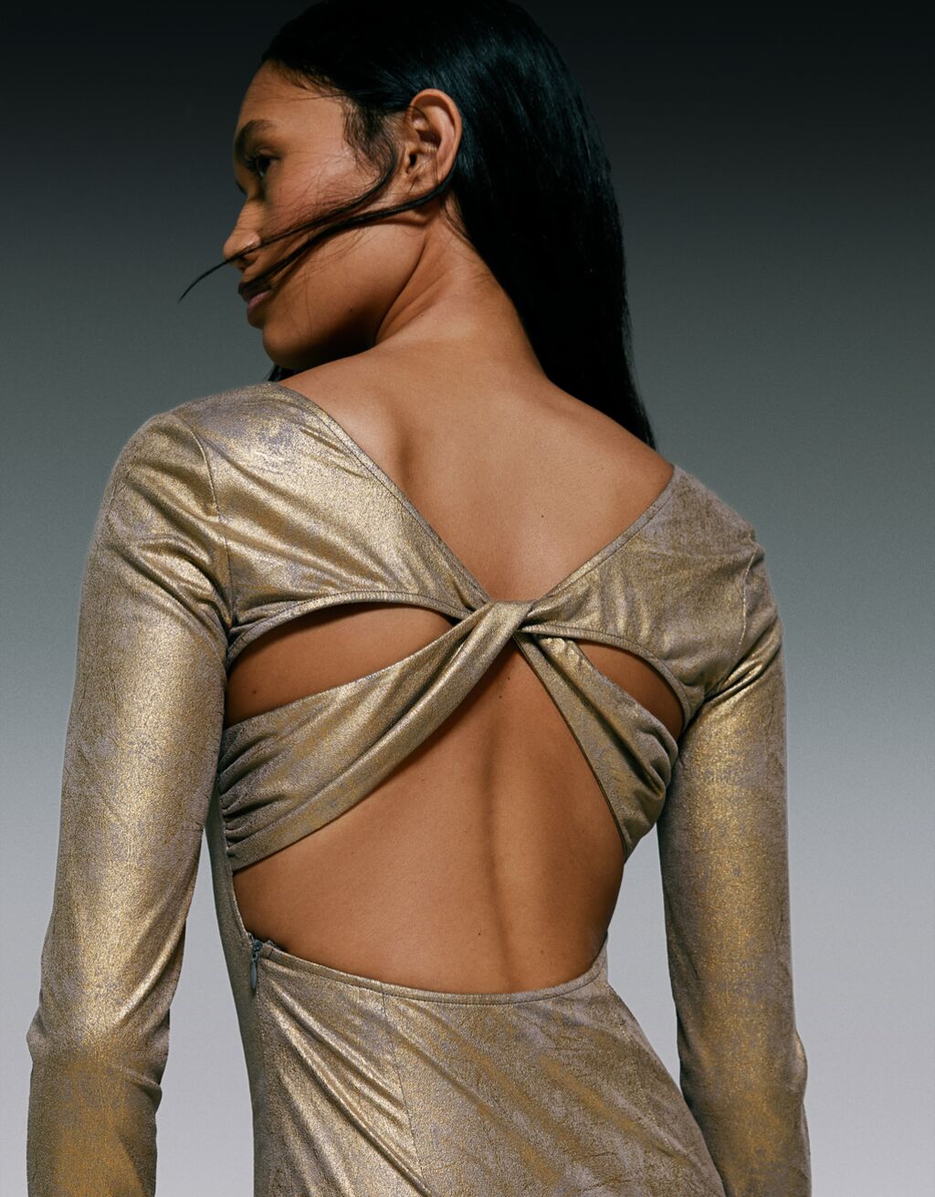 Metaliczna, dopasowana sukienka średniej długości z długim rękawem i ozdobnym elementem na plecach